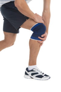 Lesiones Deportivas - Dolor en una rodilla. trauma deportes. joven deportista tiene las manos juntas una rodilla enferma para reducir un dolor.